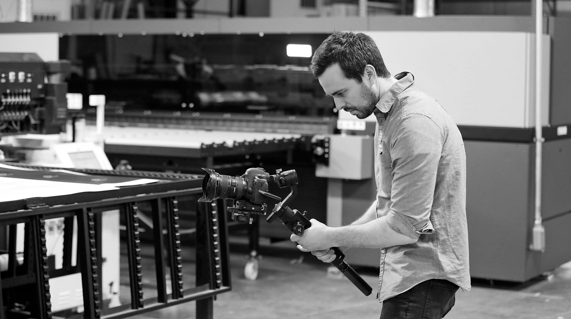 A videographer filming with a gimbal on a shop floor
